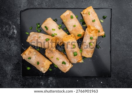 Crispy fried spring rolls Lumpia on slate plate with soy sauce sesame chopsticks and copy space top view.