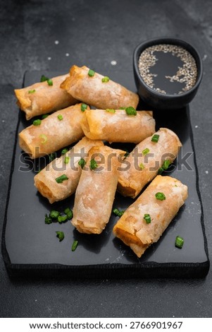 Crispy fried spring rolls Lumpia on slate plate with soy sauce sesame chopsticks and copy space top view.