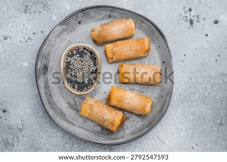 Crispy fried spring rolls served with soy dipping sauce and sesame seeds Asian appetizer flat lay on stone background.