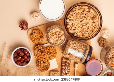 Crispy granola in a bowl, granola bars, honey and glass of milk, hazelnuts on a wooden desk from above on a beige background. Idea for breakfast. - Powered by Shutterstock