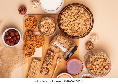 Crispy granola in a bowl, granola bars, honey and glass of milk, hazelnuts on a wooden desk from above on a beige background. Idea for breakfast. - Powered by Shutterstock