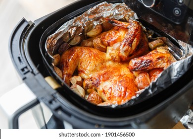 Crispy honey and lemon roasted chicken with potatoes in an air fryer under natural light - Shutterstock ID 1901456500