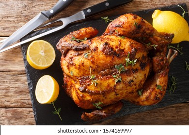 Crispy juicy rotisserie chicken close-up on a slate board on the table. Holiday dish. Horizontal top view from above - Shutterstock ID 1574169997