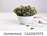 Crispy nori seaweed on bowl on grey background. Traditional Japanese dry seaweed sheets. Healthy snack. 