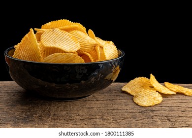 Crispy potato chips in a bowl on wooden with black background - Powered by Shutterstock