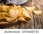 Crispy Potato Chips on cutting board on a wooden table.