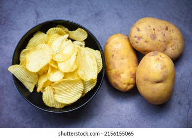 Crispy Potato Chips On The Kitchen Table And Fresh Raw Potatoes On Dark Background, Potato Chips Snack On Bowl