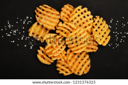 Crispy potato waffles fries, wavy, crinkle cut, criss cross cries on black background