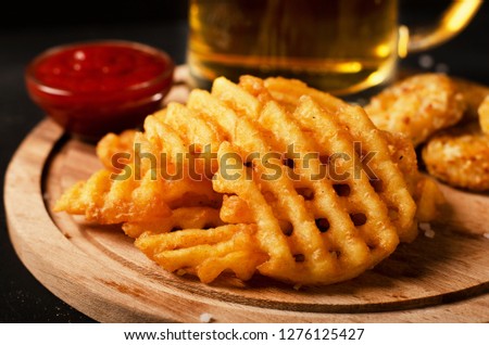 Crispy potato waffles fries, wavy, crinkle cut, criss cross cries with on a cutting board