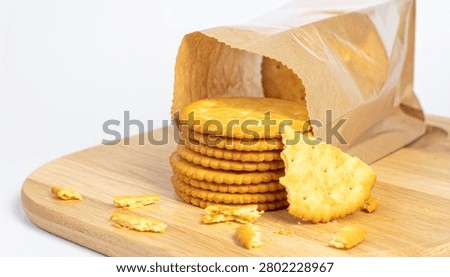 Crispy round biscuit crackers with stack and broken pieces, paper plastic takeaway bag package, wooden serving board isolated mockup.