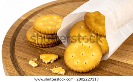 Crispy round biscuit crackers with stack and broken pieces, paper plastic takeaway bag package, wooden serving board isolated mockup.