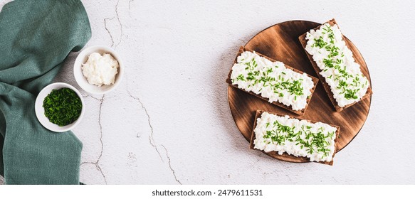 Crispy rye bread with cottage cheese and green onions on a board top view web banner