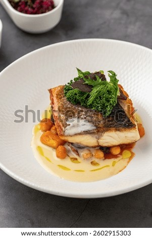 Crispy skinned pan seared fish fillet with chickpeas, creamy sauce, and fresh greens