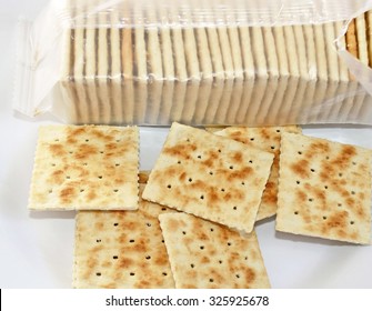 Crispy soda crackers on plate. Open package in background - Powered by Shutterstock