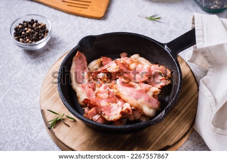 Crispy strips of bacon fried in a pan on the table.