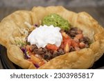 Crispy tostada shell contains this generous fajita taco salad with large scoops of sour cream and guacamole on top.