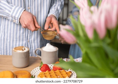 The crispy waffles, red strawberries on a beautiful white plate. Donuts, strawberries, a bowl of cinnamon, coffee with whipped cream in cups. Coffee advertising - Shutterstock ID 2279708729