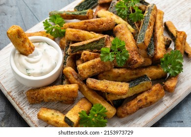 Crispy zucchini fries with sauce in white wooden board