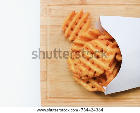 Criss Cut Fries in Take Away White Box on Wooden Board Plate. Fast Food meal freshly made from natural potatoes isolated with empty copy space top view. Unhealthy eating, take out, fast food concept
