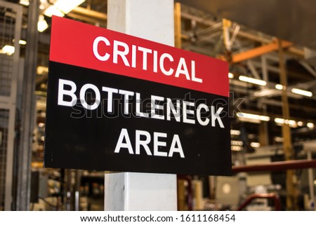 Critical Bottleneck Area sign in industrial factory setting