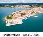 Croatian town of Porec, shore of blue azure turquoise Adriatic Sea, Istrian peninsula, Croatia. Bell tower, red tiled roofs of historical buildings, boat, piers.  Euphrasian Basilica. Aerial view. 