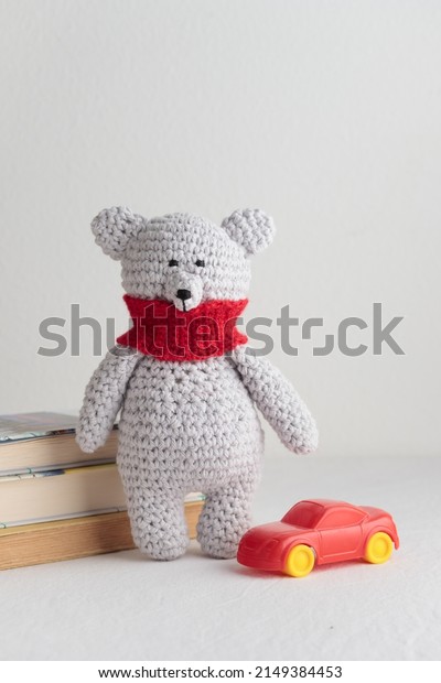 Crochet knitting cute teddy bear with books and a\
toy on a white table