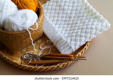 Crochet work with cotton yarn, yarn balls and wood crochet needles on threshing basket. Handmade and crochet hat. Slouch or beanie hat.