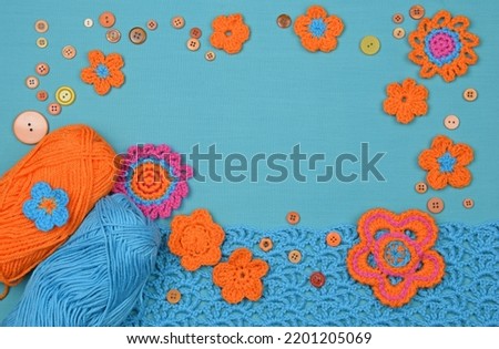 Crocheted motifs, buttons, and skeins on the blue textile background.
