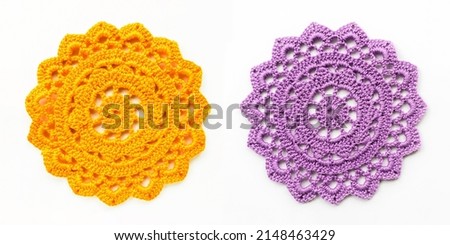 Crocheted yellow and purple lace doily close-up on a white background. Needlework, crochet.