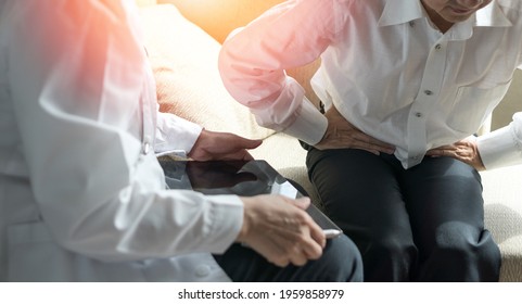 Crohn's Disease Or Ulcerative Colitis Concept. Doctor Physician With Computer Tablet Consulting With Male Patients Stomach Ache In Hospital Exam Room. Men's Health Technology.