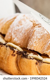 Croissant With Banana And Nutella In Powdered Sugar On A White Plate