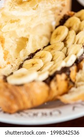 Croissant With Banana And Nutella In Powdered Sugar On A White Plate