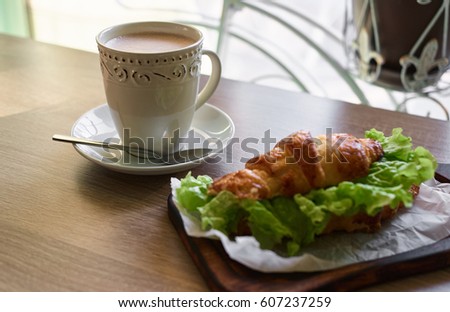 Croissant and hot chocolate for morning meal. Breakfast. Sandwich. Flowers.