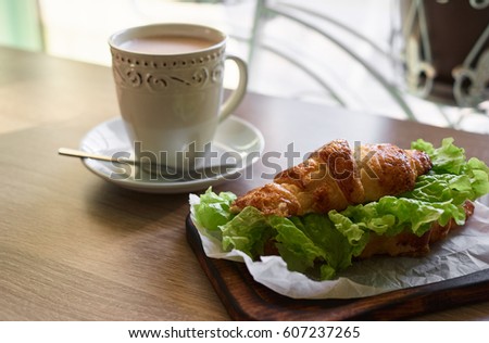 Croissant and hot chocolate for morning meal. Breakfast. Sandwich. Flowers.