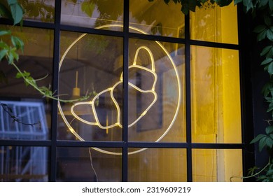 Croissant neon light sign hanging on café window. Generic croissant logo for pastry shop. - Powered by Shutterstock