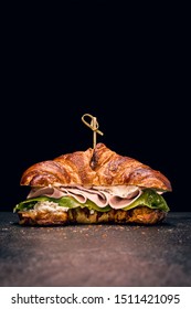 Croissant Sandwich With Fresh Salad, Ham And Cream Cheese On Dark Background. Light From Above