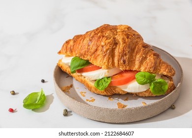 Croissant Sandwich With Mozzarella, Tomato And Basil In A Plate On White Background. Italian Breakfast. Tasty Food