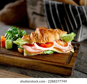 Croissant sandwich stuffed with fresh vegetables, ham, Semi-hard cheese. Close-up. Macro. Isolated on a brown background. Fusion cusine (French-American).
