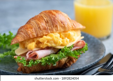 Croissant sandwich with turkey ham, scrambled eggs, cheese and lettuce salad. Continental style breakfast