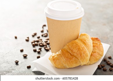 Croissants with coffee to go in a paper cup, take away breakfast