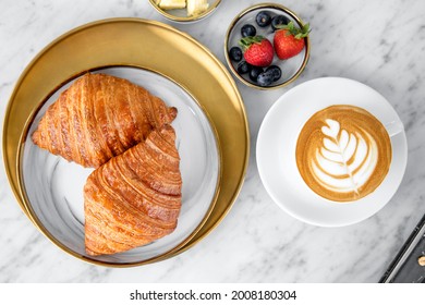Croissants with coffee. Two Diamond croissants on plate and cup of Latte coffee on white marble background, top view

