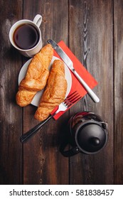 croissants on a plate, a knife with a red circle on a red napkin.