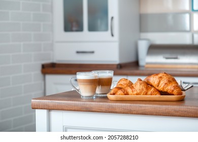 Croissants and two Coffee with milk in Breakfast time on brown kitchen table. Couple Cappuccino in transparent cups and French croissants on board for Romantic breakfast in Home cozy kitchen interior - Powered by Shutterstock