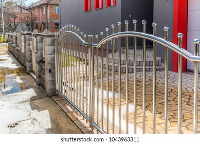 Crome fence with gate on concrete bricks wall. Stainless steel fence