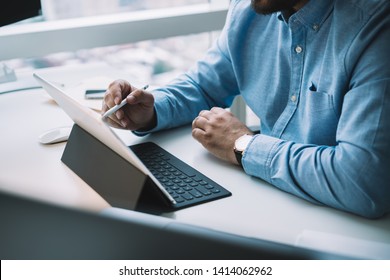 Crop Adult Man In Blue Shirt Tapping Modern Tablet With Stylus While Working At White Computer Desk In Contemporary Office 