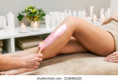 Crop Anonymous Beautician Applying Pink Wax On Leg Of Faceless Female Client During Depilation Procedure In Light Modern Spa Salon