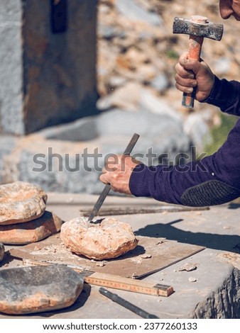 Crop anonymous craftsman cutting rock using chisel and hammer while creating stone craft on workbench in sunny day