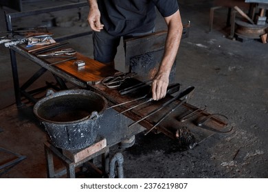 Crop anonymous male glassblower with various metal tools arranging on workbench in professional glass making factory - Powered by Shutterstock