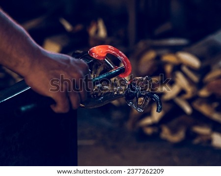 Crop anonymous master shaping glass handle on glass decanter fixed on metal bar using metal tool in glass factory