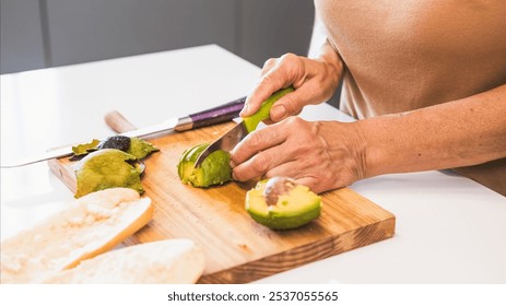 Crop anonymous mature woman cutting avocado slices with knife while preparing breakfast at kitchen island - Powered by Shutterstock